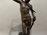 une statue antique en bronze représentant un homme tenant une lance