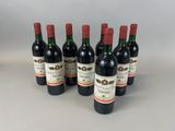 six bottles of red wine are lined up on a table