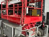 une cisaille rouge entreposée dans un entrepôt avec d'autres équipements