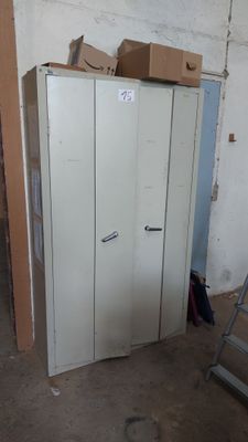 une armoire métallique au milieu d'une pièce, sur laquelle sont posées des boîtes