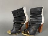 pair of black and white high heeled sandals with gold accents