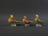 three glass birds sitting on top of each other on a black surface