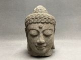 statue représentant une tête de Bouddha aux yeux fermés sur fond gris
