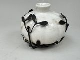 un vase blanc orné de feuilles noires