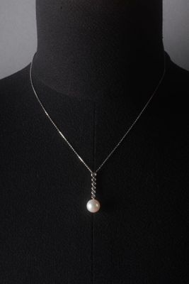 a close up of a mannequin wearing a necklace with a pearl on it