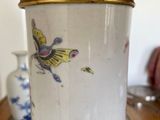 a white and gold vase with a bird on it on a table