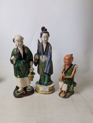 three figurines of asian people sitting on a white surface