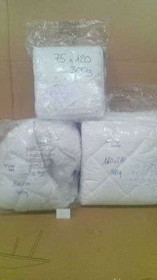 trois rouleaux de papier toilette emballés dans du plastique, posés sur une boîte en carton