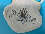 a white purse with a flower on it on a blue surface