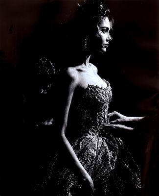 photographie en noir et blanc d'une femme en robe, debout devant un miroir