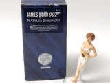 a figurine of a woman in a bathing suit next to a box of james bond 007