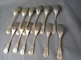 six forks and six spoons are lined up on a table