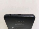 the back of a black samsung phone with a small hole in the middle