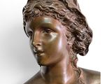 bronze bust of a woman with a hat on her head