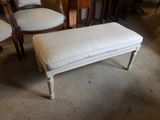 a white bench with a cushion on it in the middle of a room