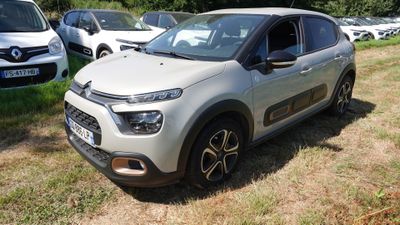 une voiture argentée garée dans un champ, avec d'autres voitures en arrière-plan
