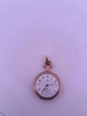 a small gold pocket watch on display on a white surface