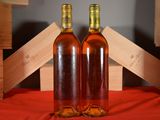 two bottles of wine sitting on a red cloth