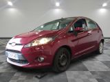 La Ford Fiesta rouge est garée dans une pièce au sol carrelé d'un motif à damier.