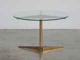 a round glass table with brass legs and a glass top