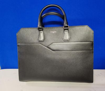 un sac à main noir posé sur une table avec un fond bleu