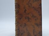 an old brown book sitting on top of a white surface