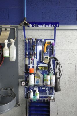 un porte-outils bleu sur lequel sont accrochés des outils, à côté d'un évier