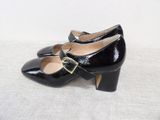 black high heeled shoes with buckles on a white surface