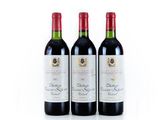 trois bouteilles de vin rouge posées l'une à côté de l'autre sur une surface blanche