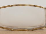 a white glass and gold frame on a table