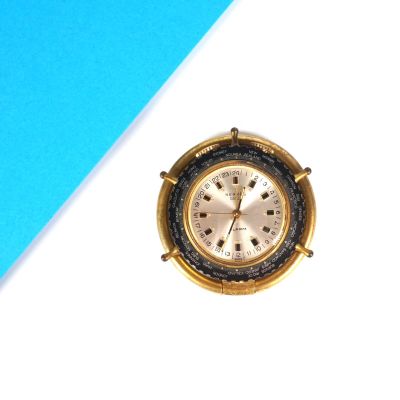 une petite horloge dorée posée sur une table bleue et blanche