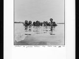 black and white photograph of a group of people floating in a body of water