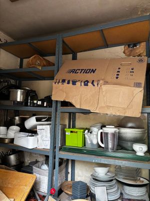 a box on a shelf in a kitchen filled with dishes and pans