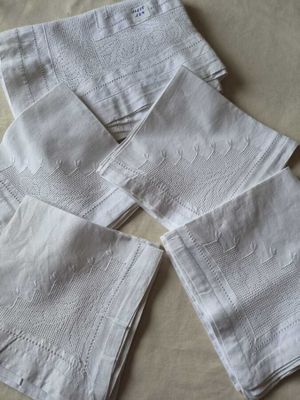 quatre serviettes en lin blanc sur une table recouverte d'une nappe blanche