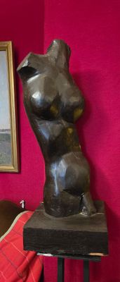 une statue représentant une femme assise sur un tabouret à côté d'un tableau