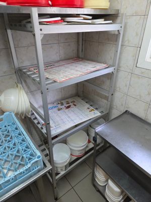 une étagère métallique sur laquelle sont posées des assiettes et des bols, dans une cuisine