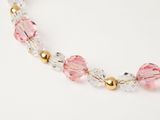 pink crystal and gold beaded necklace on a white background