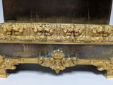 a gold frame with carvings on it and a mirror in the background