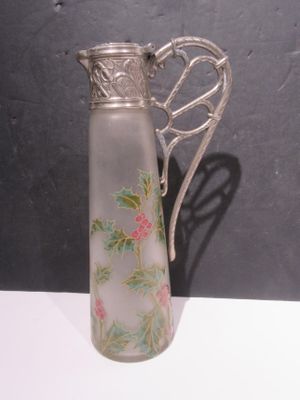 a glass pitcher with a silver handle on a table