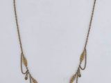 a gold plated necklace with a long chain that has a leaf design on it