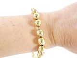 someone is wearing a bracelet with gold beads on their arm