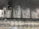 many cups and glasses on the shelf above the coffee maker