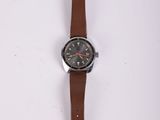 une image d'une montre sur une surface blanche avec un bracelet marron