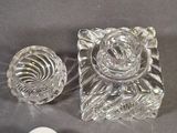 two clear glass candlesticks and a white candle holder on a gray surface