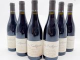 six bouteilles de vin sont alignées sur une surface blanche