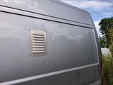 a silver van that has a vent vent on the side of it