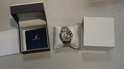 une montre dans une boîte posée sur une table, à côté d'un coffret à montres