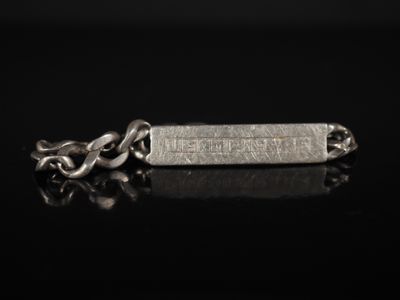 un gros plan d'un bracelet en argent muni d'une chaîne, posé sur une surface noire