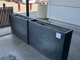 a large metal planter on the sidewalk outside of a building