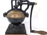 un vieux moulin à café avec un socle et une poignée en bois